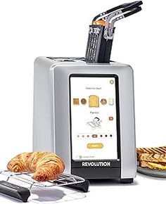 a silver toaster sitting on top of a counter next to some croissants