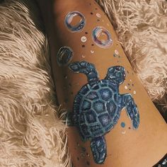 a woman's leg with an image of a turtle painted on it and bubbles