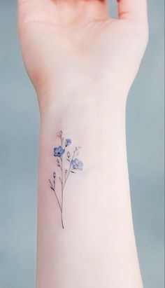 a small blue flower tattoo on the wrist