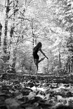 black and white photograph of a woman running through the woods with leaves on the ground