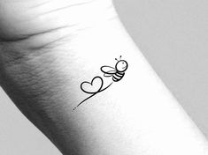 a black and white photo of a small tattoo on the wrist with a bee flying towards a heart