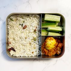 a metal container filled with rice, cucumbers and other food