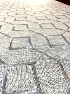 a close up view of a bed with white linens and hexagonal pattern