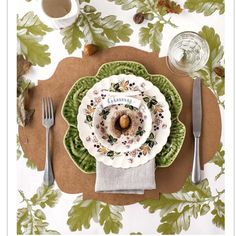 a place setting with plates, silverware and napkins on a floral tablecloth