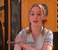 a woman sitting in front of a school bus with her hand out to the side