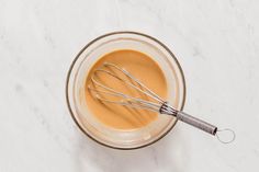 a glass bowl filled with batter and whisk on top of a white counter