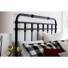 a black metal headboard with white pillows and plaid pillow cases on top of it