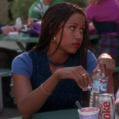 a woman sitting at a table with two soda bottles