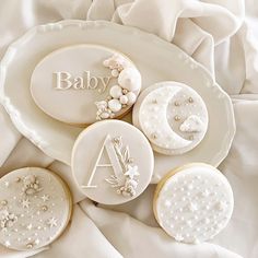 some cookies are laying on a plate with the name baby written on them and decorated with pearls