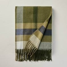 a green and blue plaid blanket hanging up on a wall with a white wall in the background