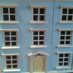 a blue doll house with white trim and windows on the front, door and window sill