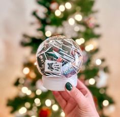 a person holding up a snow globe in front of a christmas tree