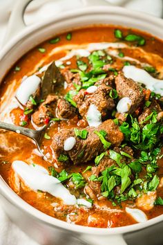 a close up of a bowl of soup with meatballs and sour cream on top