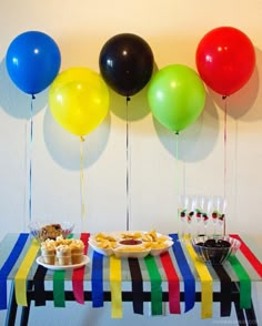 a table topped with plates of food and balloons