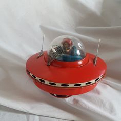 a small red object on a white sheet with some wires attached to it and a glass ball in the middle