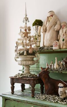 a christmas tree is sitting on top of a green dresser with other ornaments and figurines