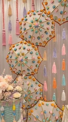 there are many colorful umbrellas hanging on the wall and some tassels around them