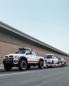 two large trucks driving down the road next to each other in front of a building