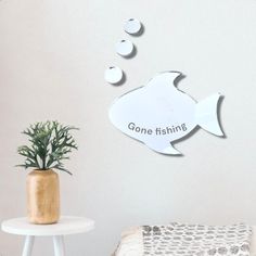 there is a fish on the wall and some bubbles in the air next to a potted plant