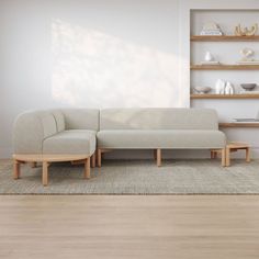 a white couch sitting on top of a wooden floor next to a shelf filled with vases