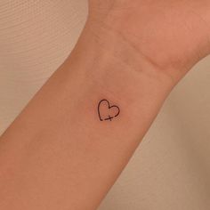 a small heart tattoo on the wrist