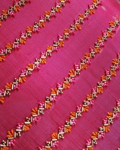 pink and orange fabric with gold trimmings on the edges, close up view