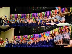 a group of people standing around each other in front of a stage with balloons and streamers