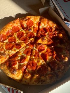 a pepperoni pizza sitting in a box on top of a table