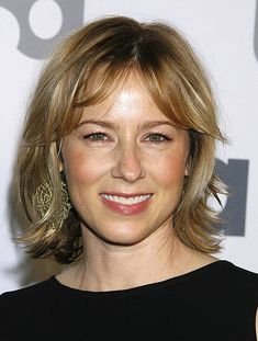 a close up of a person wearing a black dress and smiling at the camera with an earring on