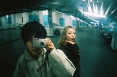 two people are taking pictures with their cameras in an underground subway car area, one is holding a camera and the other is looking at something