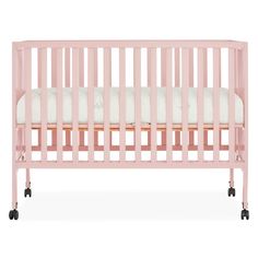 a pink crib with white sheets and black wheels on the bottom, in front of a