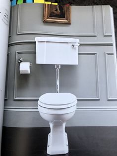 a white toilet sitting in a bathroom next to a painting