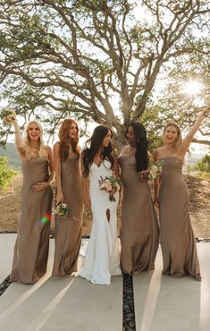 the bride and her bridesmaids pose for a photo in front of a tree