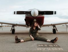 a woman sitting on the ground in front of an airplane