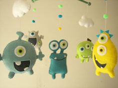 three stuffed toys hanging from the ceiling with eyes and noses on them, one is yellow, one is green