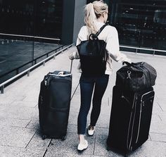 a woman with two suitcases walking down the street