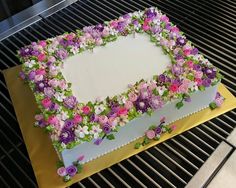 a cake with flowers on it sitting on top of a grill grates and is ready to be cut