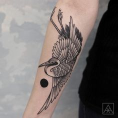 a black and white bird tattoo on the left arm with an arrow in it's beak