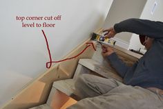 a man is working on a wall with red tape and a level to the floor