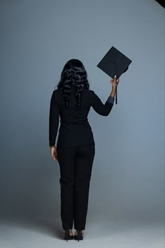 a woman in black holding up a graduation cap