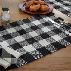 black and white checkered table cloth with utensils on it, next to a plate of food