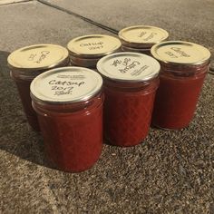 six jars of jam sitting on the ground