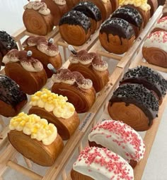 many different types of pastries sitting on a wooden rack together with white frosting and red sprinkles