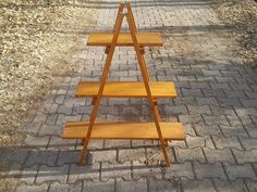 three wooden shelves sitting on the side of a brick road