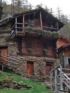 an old stone house with plants growing on the roof