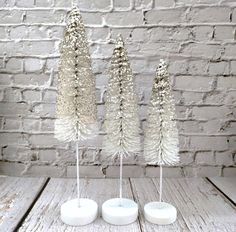 three white candles are sitting on a table next to some pine cones and snow flakes