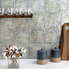 a vase filled with cotton flowers sitting on top of a counter next to two salt and pepper shakers