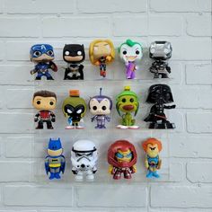 a bunch of pop - up action figures are hanging on a brick wall with white bricks behind them