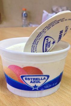 a plastic cup filled with yogurt sitting on top of a wooden table