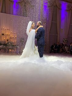 a bride and groom standing in the middle of a cloud filled dance floor at their wedding reception